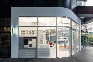 A modern coffee shop with a predominantly white interior, large windows, and various appliances, creating a bright and welcoming atmosphere