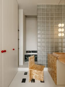 A modern kitchen with a tile wall, marble countertops, and a dimly lit atmosphere, featuring a sink, cabinet, and chair