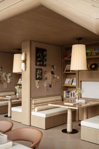 Cozy modern study with wooden walls, a wooden table, and scattered books, featuring a TV on the wall