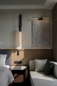 A well-lit bedroom with a bed, couch, and table, featuring predominantly white materials and a comfortable atmosphere