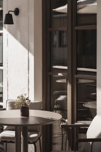 A modern dining space with a wooden table and metal chairs, surrounded by a window with natural light, creating a warm and inviting atmosphere