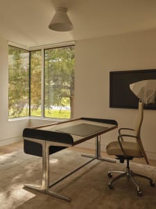 A home office with a black desk and white chair, situated next to a window for natural light, in a clean and organized space
