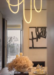 A dimly lit modern living space with a large pile of hay, chairs, and a dining table, filled with natural light