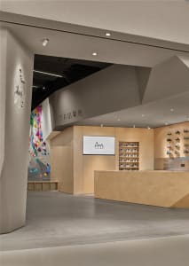 A dimly lit shoe store with a wooden counter and TV on the wall, surrounded by displayed shoes