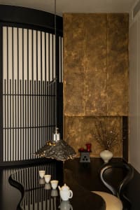 Dining area with a brown wall, a wooden table, and a potted plant, featuring a cozy and warm atmosphere