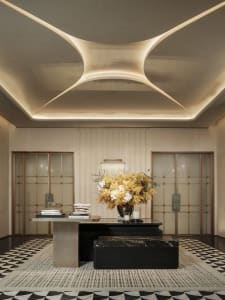 Bright and welcoming lobby with a marble floor, a black desk, and a bookshelf, illuminated by natural light