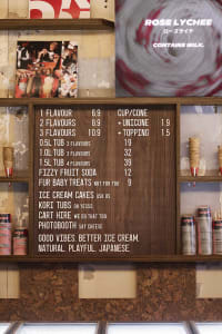 A wooden menu board with a brown color, featuring a variety of food items and drinks in English and Japanese, creating an inviting atmosphere