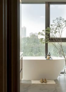 Bathroom with a white bathtub, a window, and a potted plant, creating a calm and inviting atmosphere