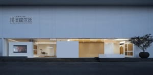 A modern office building with a white facade and a glass door, set against a bright and sunny background
