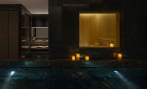 Dimly lit modern bathroom with a large window, black bathtub, sink, and toilet, creating a moody atmosphere