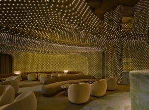A large, well-lit room with a high ceiling, featuring couches, chairs, and dining tables, arranged in a contemporary and sophisticated style for comfort and functionality