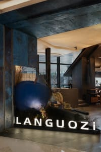 Cozy restaurant interior with blue walls, potted plants, and a blue apple sculpture, featuring a modern and stylish atmosphere with dim lighting
