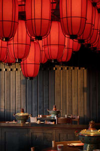Cozy dining space with a wooden table, red lanterns, and comfortable seating