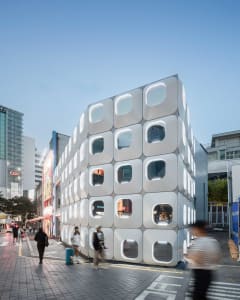A modern office building with a minimalist design, featuring a large number of windows and a sleek appearance, set in an urban environment with natural light and a bright atmosphere