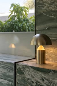 A modern living space with a marble countertop, a gold lamp, and natural light from a large window