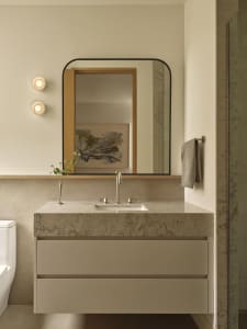 Bathroom with a white color scheme, dim lighting, and a marble sink, mirror, and towel rack