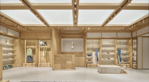 Well-lit modern store with wooden floors and walls, featuring a couch, chair, bench, shelves, and cabinets