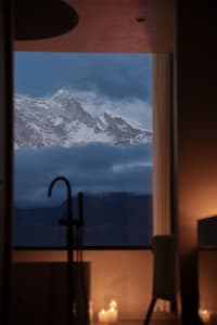 A serene bathroom with a window overlooking a snow-covered mountain range, allowing natural light to enter the room