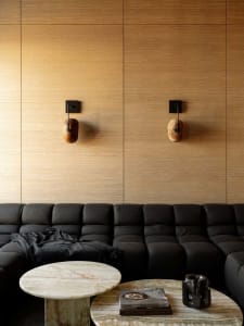 A modern living room with a wooden wall, a wooden table, and a comfortable atmosphere created by well-placed lighting