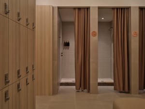 Bathroom with a brown shower curtain, bench, and floor, featuring wood and brown tiles in a well-lit space