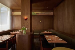 A warm and inviting restaurant dining area with wooden elements, multiple tables, chairs, and soft lighting