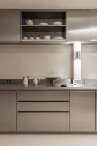 A modern kitchen with a stainless steel countertop and sink, set in a dimly lit space with a cozy atmosphere