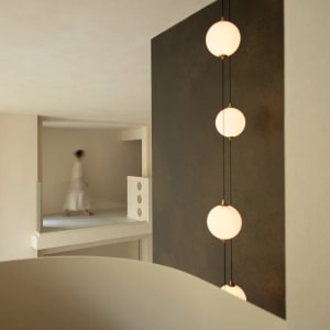 A dimly lit living room or hallway with a woman in a white dress, black and white color scheme, and modern minimalist style