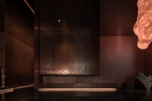 Dimly lit room with a brown wall, a bench, and a sense of depth from a low-angle perspective
