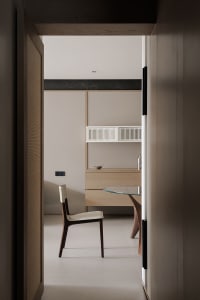 A modern kitchen with a white countertop, glass table, and a chair, set in a dimly lit space