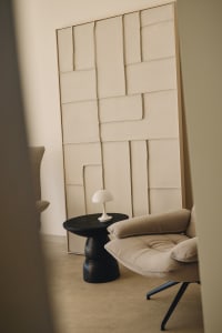 Contemporary living room with a couch, chair, and table, featuring a large abstract painting and neutral colors, with soft and diffused lighting