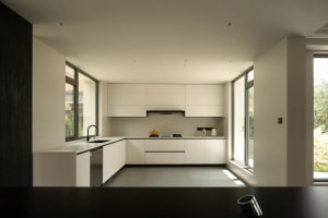A modern kitchen with white cabinets, a black countertop, and dim lighting creating a cozy atmosphere