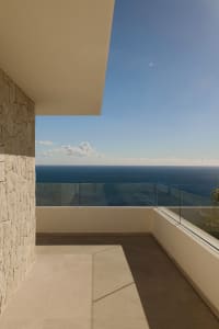 A serene oceanfront balcony with a glass railing, overlooking the vast ocean and sky