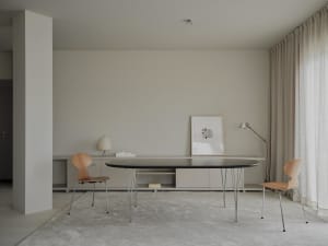 A well-lit living room with a central table surrounded by chairs and a lamp, featuring a clean and modern design