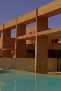 A modern house with a swimming pool surrounded by a stone wall, featuring a unique design with brown and orange colors, creating a relaxing and inviting atmosphere