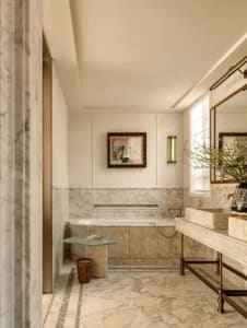 Bathroom with a white marble countertop, a marble sink, and a large mirror above the sink, with a potted plant on the countertop, in a soft and warm lighting environment