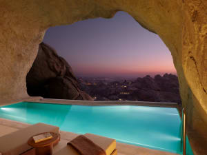 A serene outdoor space with a blue pool surrounded by a rocky landscape in a desert valley