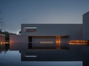 A large modern building with a glass exterior reflected in a pool of water, creating a visually striking scene with a sense of elegance and sophistication