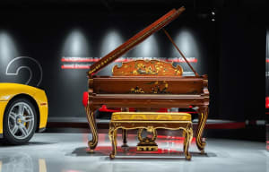 A photograph of a piano in a living space with a hardwood floor, a chair, and a couch in the background, creating an elegant and sophisticated atmosphere