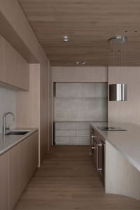 Warm and elegant kitchen with wooden cabinets, marble countertop, sink, oven, and refrigerator, dim lighting creating a cozy atmosphere