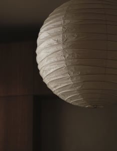 A dimly lit room with a unique paper lamp hanging from the ceiling, the focus is on the lamp