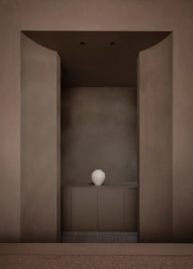 A small, simple room with a brown color scheme and a white vase on a counter as the main point of interest