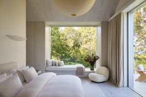 Bedroom with a bed, bench, and window, featuring wood and fabric materials in a calm and relaxing environment
