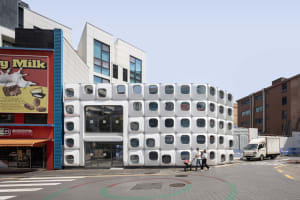 Photograph of a modern building with a circular shape and white facade in a busy urban city setting