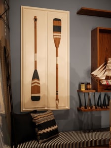 Cozy living space with a blue wall, wooden cabinet, and wooden canoes hanging above, featuring a chair and couch