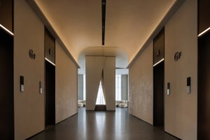 A large white room with a high ceiling, lined with doors and featuring a large window, creating a clean and spacious atmosphere