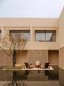 A modern patio with a table and chairs surrounded by a concrete base, with a bench nearby, and natural sunlight creating a warm atmosphere