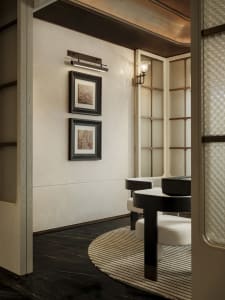 A dimly lit dining area with a wooden table and chairs, surrounded by a predominantly white room