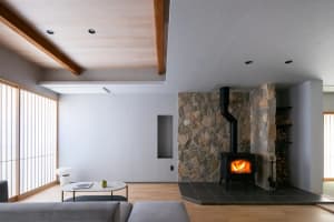 Cozy living room with a stone fireplace, a couch, a chair, and a dining table, surrounded by stone and creating a warm atmosphere