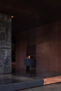 Bathroom with a black marble countertop, sink, and mirror in a modern space with dim lighting