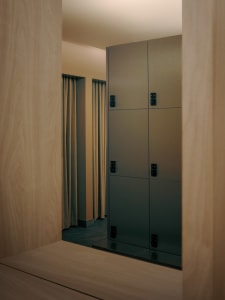 Bathroom with a gray metal cabinet and wooden floor, dimly lit with a towel rack visible through an open door